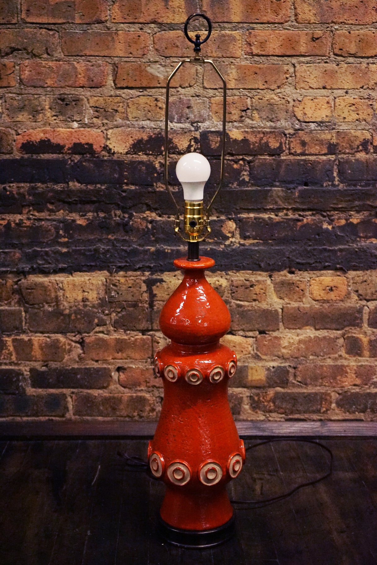 A stunning and unusual mid-century pottery lamp. The lamp has a lovely vermilion glaze and interesting shape.  reminiscent of works by Raymor and Bitossi.