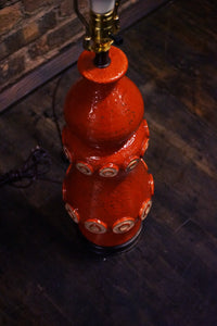 A stunning and unusual mid-century pottery lamp. The lamp has a lovely vermilion glaze and interesting shape.  reminiscent of works by Raymor and Bitossi.
