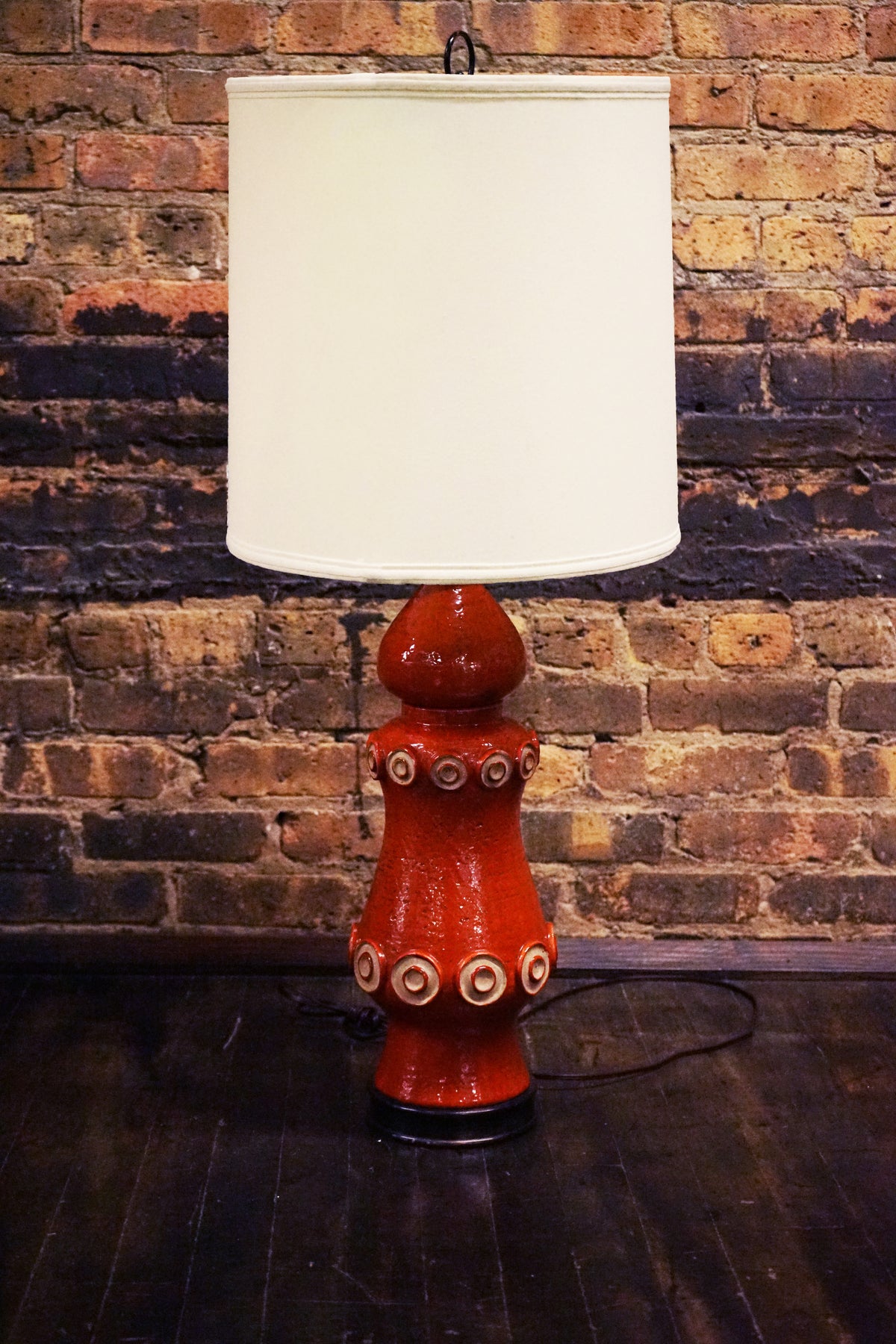 A stunning and unusual mid-century pottery lamp. The lamp has a lovely vermilion glaze and interesting shape.  reminiscent of works by Raymor and Bitossi.