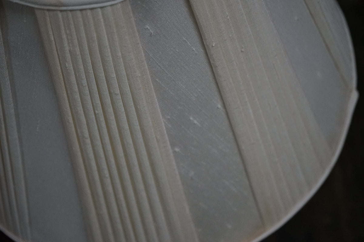 Close-up of a white lampshade with ribbed texture on a dark background