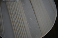 Close-up of a white lampshade with ribbed texture on a dark background