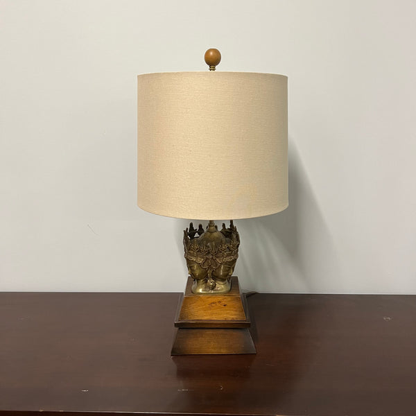 Stunning and unique vintage table lamp. It sits on a wood base. There are 4 crowned asian female faces as part of the base. They appear to be cast in brass or bronze. 