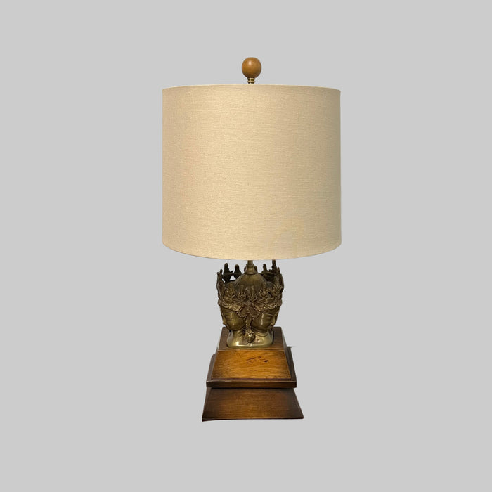 Stunning and unique vintage table lamp. It sits on a wood base. There are 4 crowned asian female faces as part of the base. They appear to be cast in brass or bronze. 