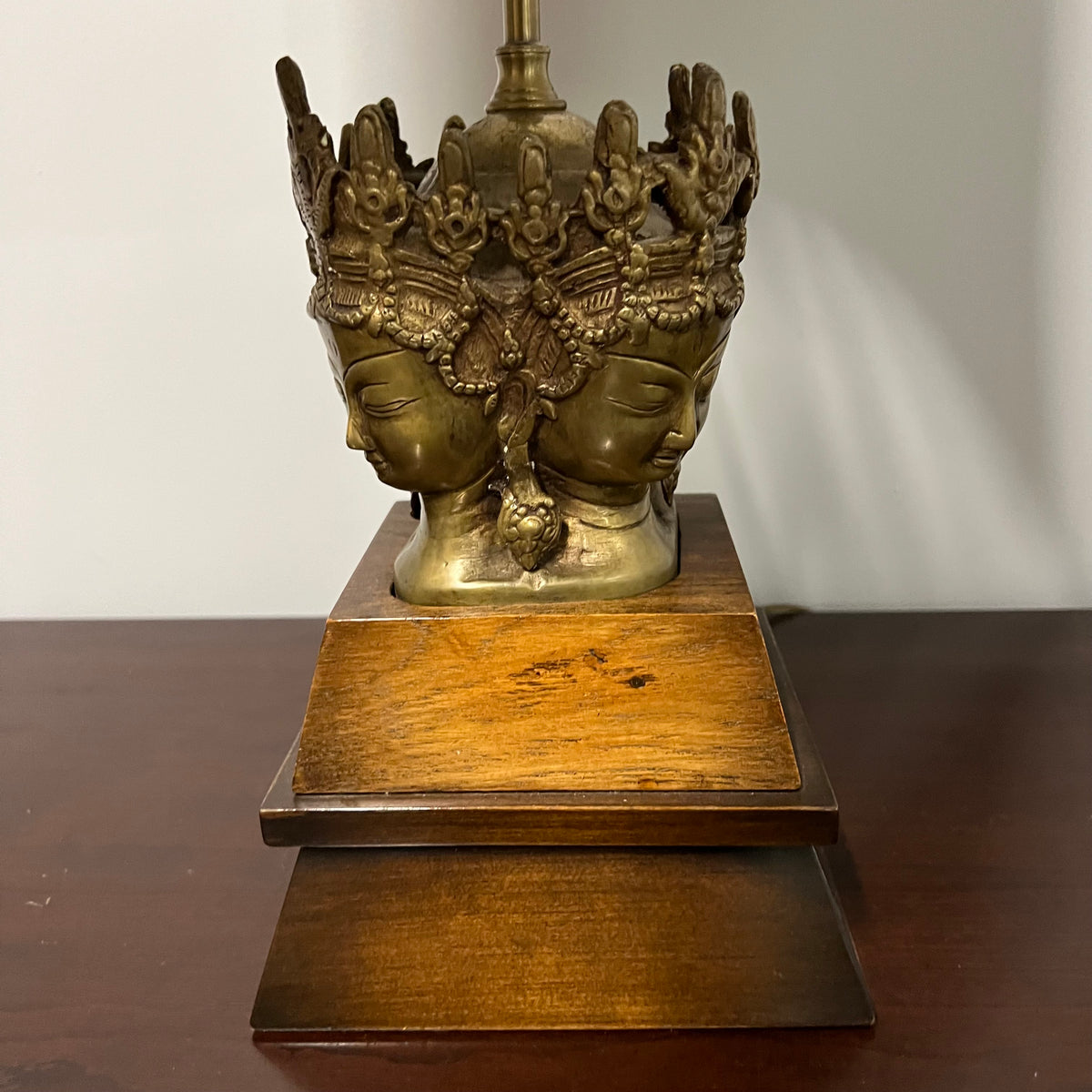 Stunning and unique vintage table lamp. It sits on a wood base. There are 4 crowned asian female faces as part of the base. They appear to be cast in brass or bronze. 