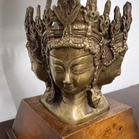 Stunning and unique vintage table lamp. It sits on a wood base. There are 4 crowned asian female faces as part of the base. They appear to be cast in brass or bronze. 