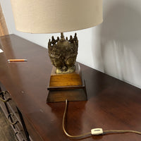 Stunning and unique vintage table lamp. It sits on a wood base. There are 4 crowned asian female faces as part of the base. They appear to be cast in brass or bronze. 
