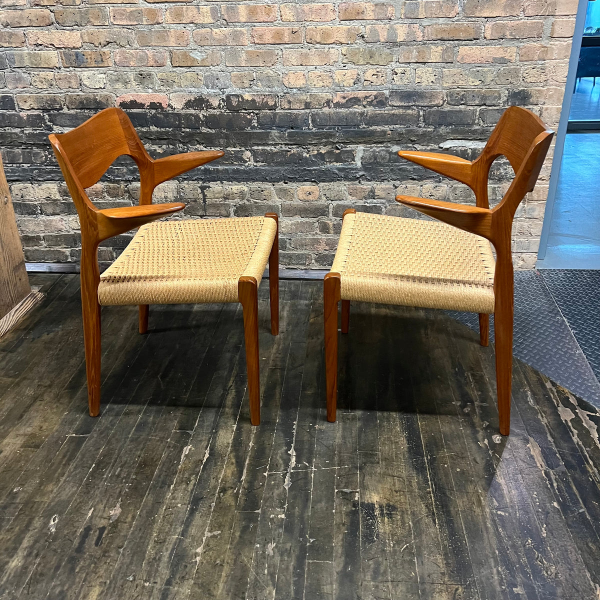 Pair of Niels Møller Model 55 captain's chairs in teak have Danish cord seats and beautifully sculpted teak arms that appear to float off the central frame