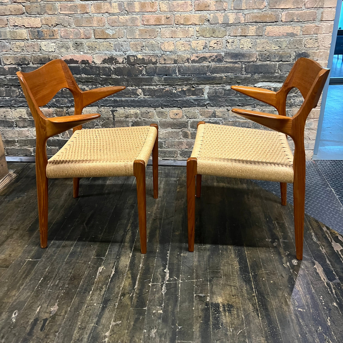 Pair of Niels Møller Model 55 captain's chairs in teak have Danish cord seats and beautifully sculpted teak arms that appear to float off the central frame