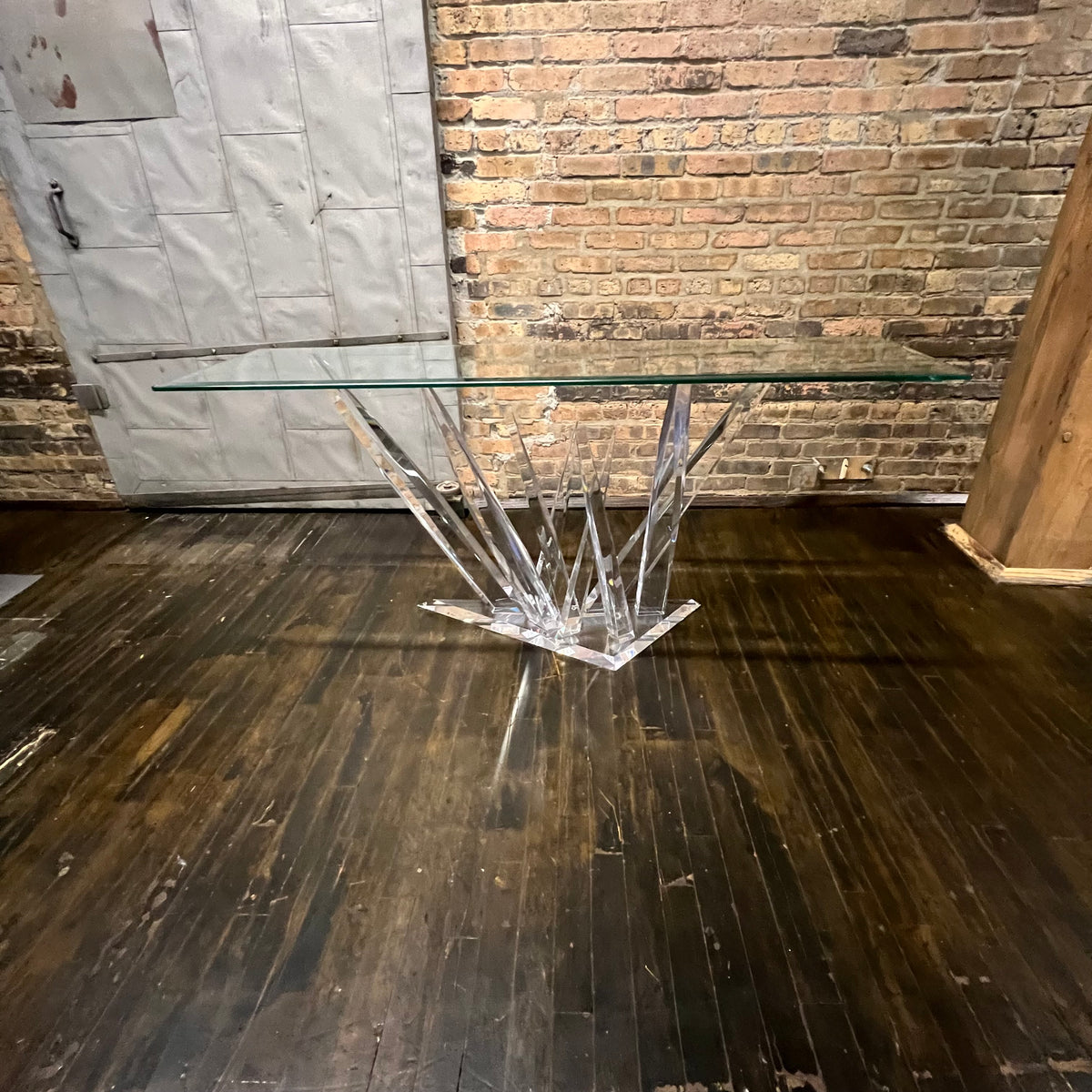 A console table with a glass top and lucite base that almost appears to be stalagmites or ice crystals