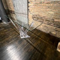 A console table with a glass top and lucite base that almost appears to be stalagmites or ice crystals