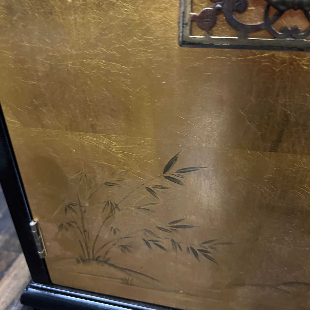Chinoiserie style black lacquer cabinet with gilded (golden) doors that have images of birds, mountains and grasses painted in the gilding.  