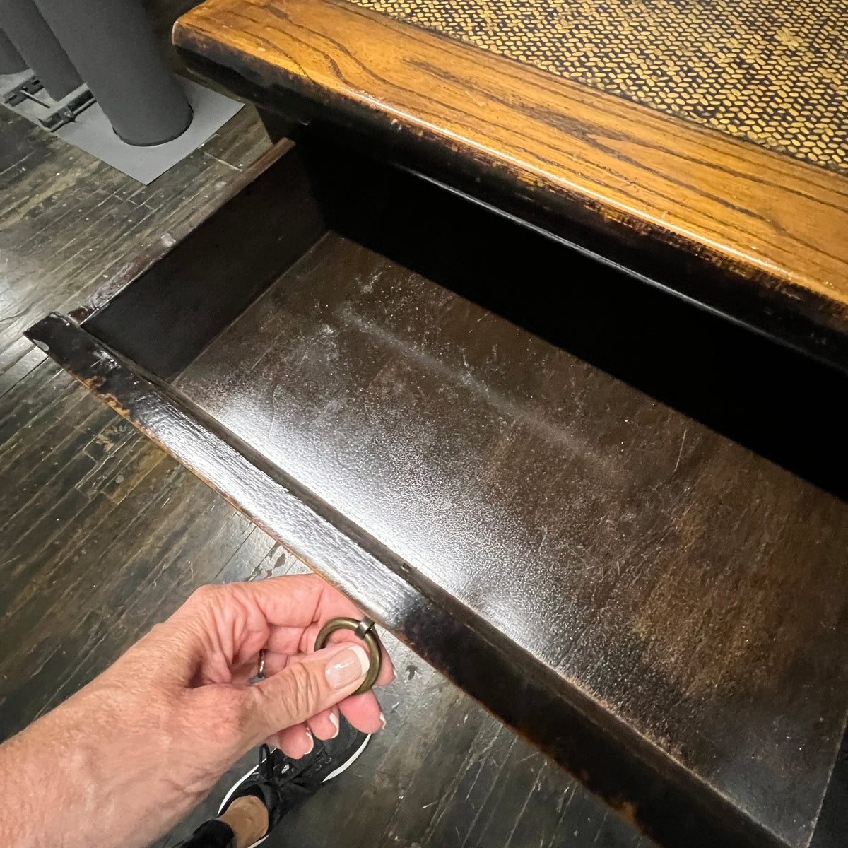 Black lacquer desk that has two "S" shaped legs that cross each other (a sort of hourglass shape). There is a smooth rattan inlay set within the desk's work surface. It has three drawers for storage with simple hardware.