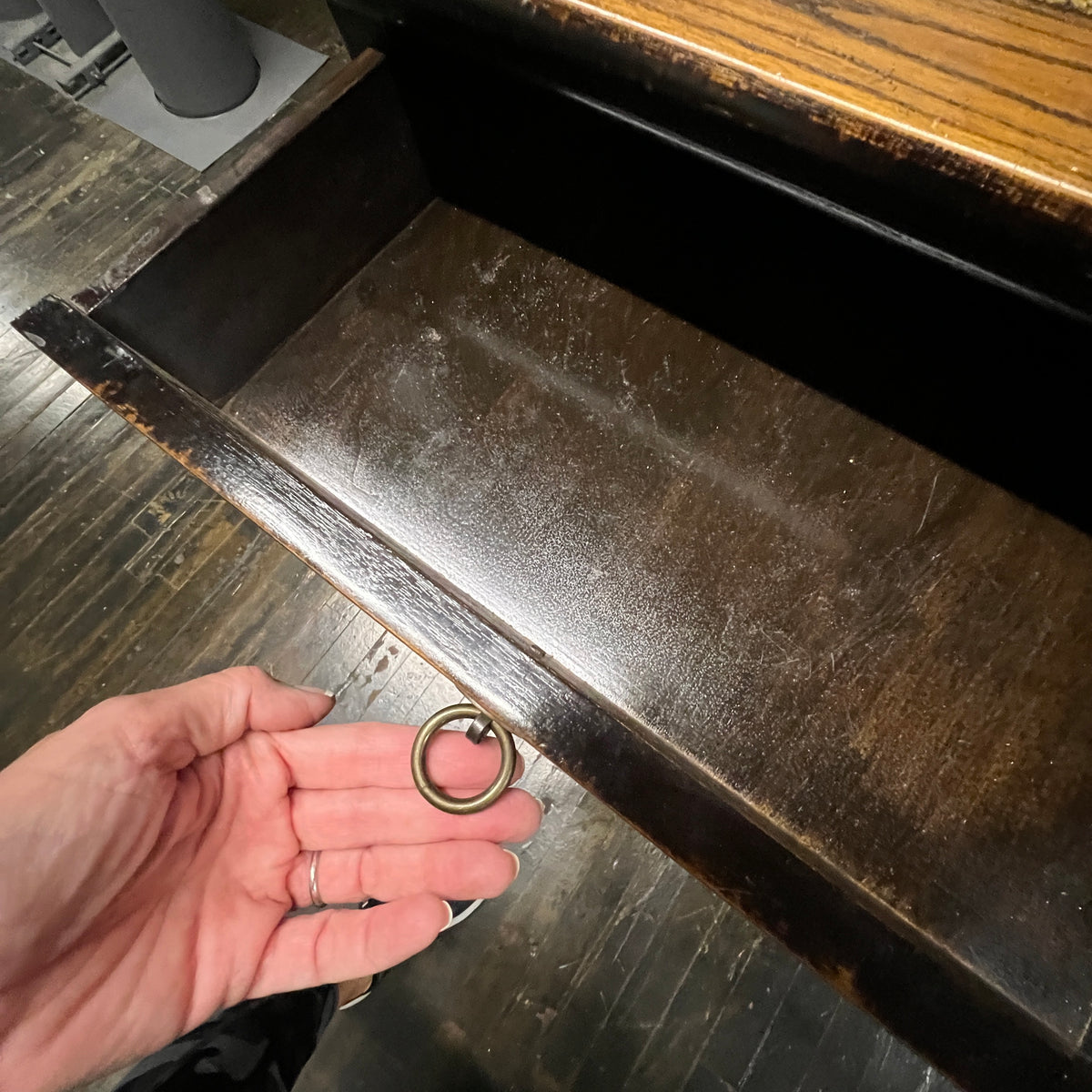 Black lacquer desk that has two "S" shaped legs that cross each other (a sort of hourglass shape). There is a smooth rattan inlay set within the desk's work surface. It has three drawers for storage with simple hardware.