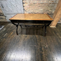 Black lacquer desk that has two "S" shaped legs that cross each other (a sort of hourglass shape). There is a smooth rattan inlay set within the desk's work surface. It has three drawers for storage with simple hardware.