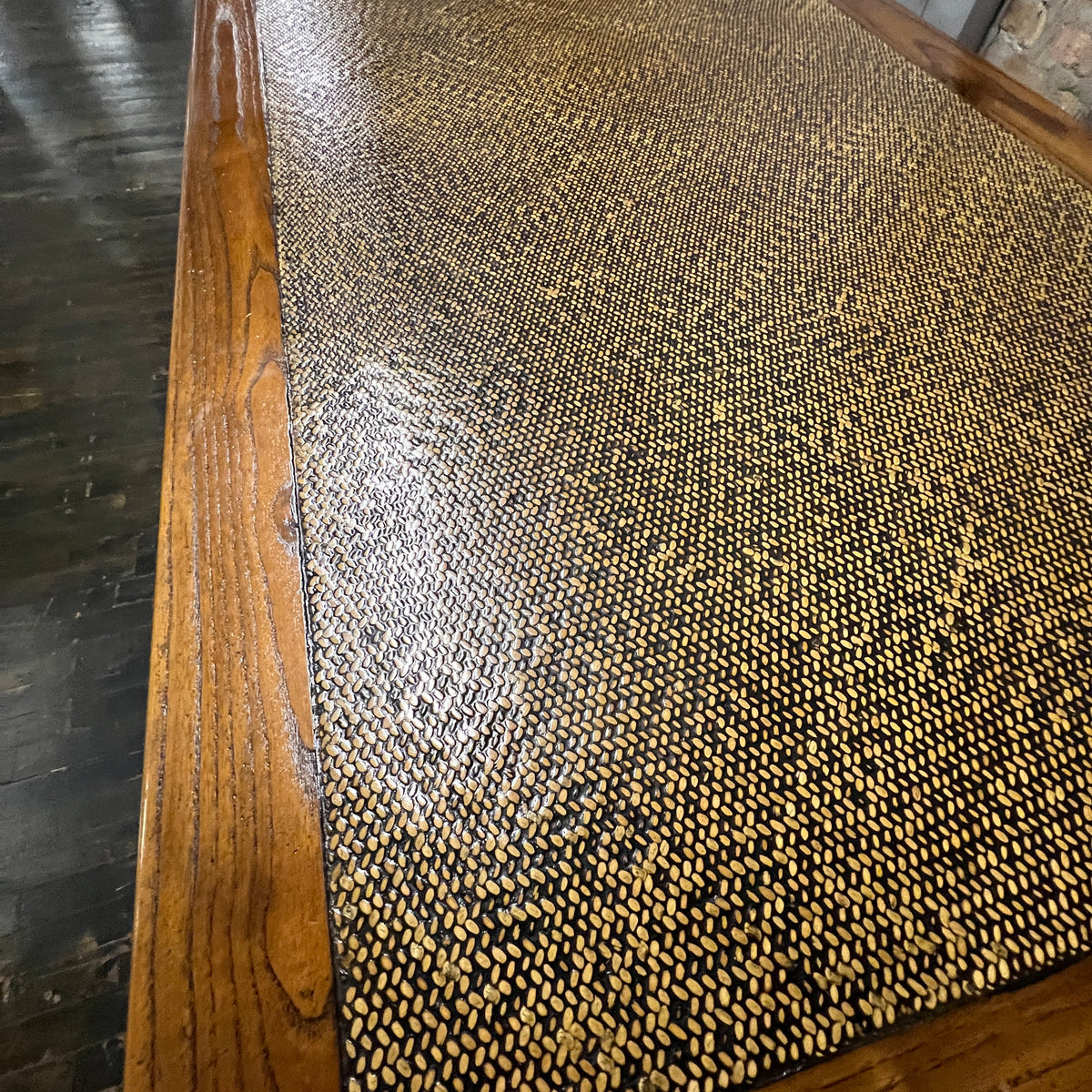 Black lacquer desk that has two "S" shaped legs that cross each other (a sort of hourglass shape). There is a smooth rattan inlay set within the desk's work surface. It has three drawers for storage with simple hardware.