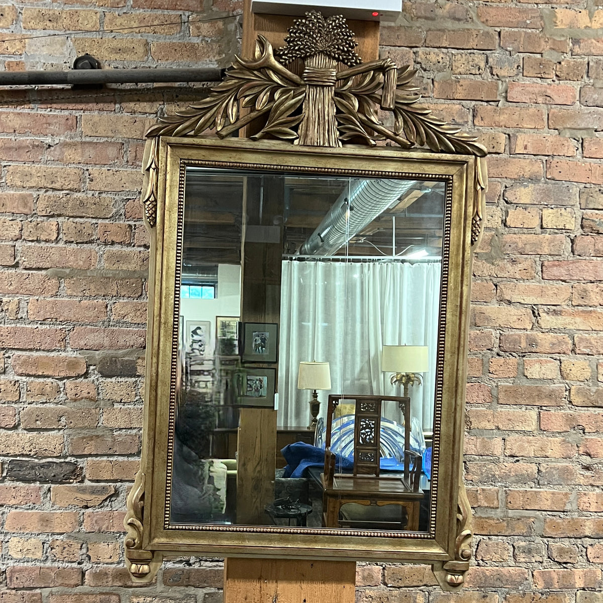 Lovely gilt mirror, one of two available.  At the top of the mirror there is a sheaf of wheat, crescent and laurel leaves at the top and beautiful details at the sides and bottom of the mirror frame.  
