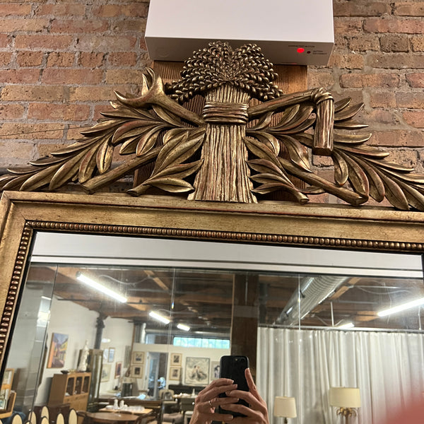 Lovely gilt mirror, one of two available.  At the top of the mirror there is a sheaf of wheat, crescent and laurel leaves at the top and beautiful details at the sides and bottom of the mirror frame.  