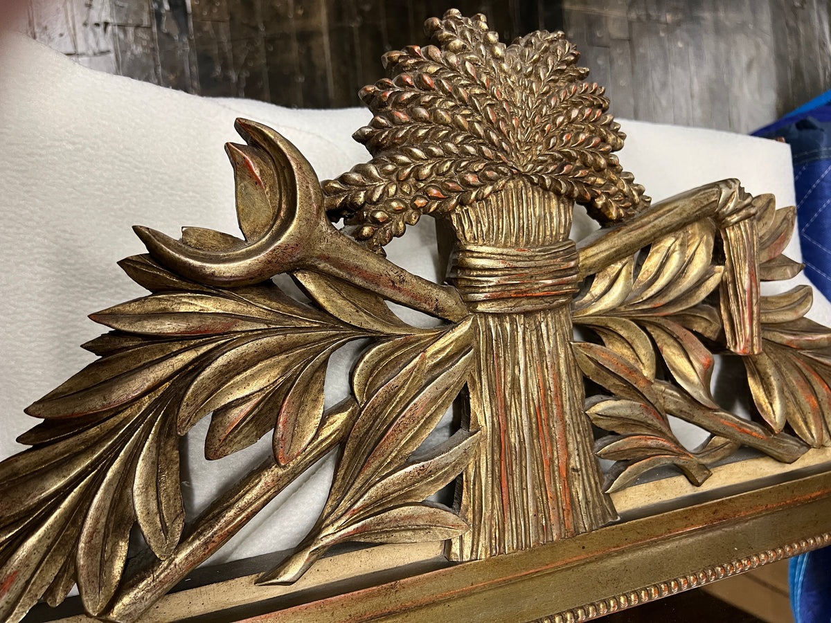 Lovely gilt mirror, one of two available.  At the top of the mirror there is a sheaf of wheat, crescent and laurel leaves at the top and beautiful details at the sides and bottom of the mirror frame.  
