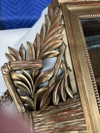 Lovely gilt mirror, one of two available.  At the top of the mirror there is a sheaf of wheat, crescent and laurel leaves at the top and beautiful details at the sides and bottom of the mirror frame.  