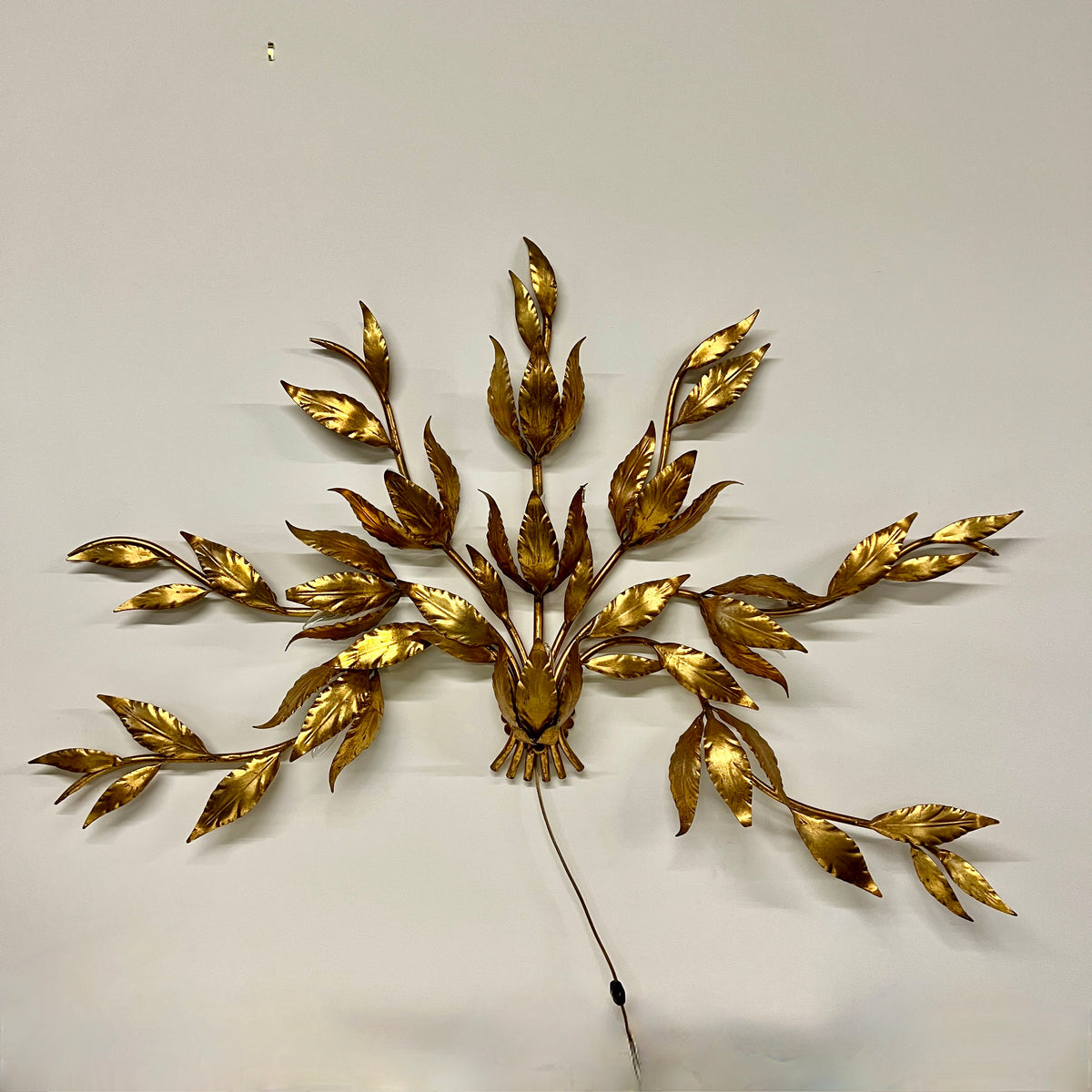 Stunning large gilded wall sconce by Hans Kogl. It has seven arms that have gilded leaves on branches.  Lights are hidden behind certain leaves.  Hollywood Regency Style.  Mid-century corded sconce.