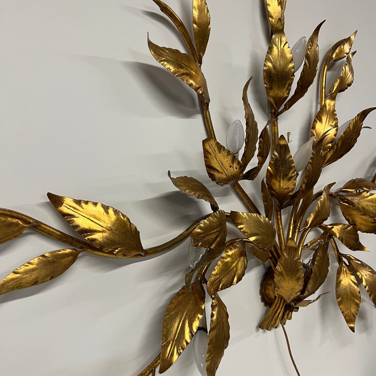 Stunning large gilded wall sconce by Hans Kogl. It has seven arms that have gilded leaves on branches.  Lights are hidden behind certain leaves.  Hollywood Regency Style.  Mid-century corded sconce.