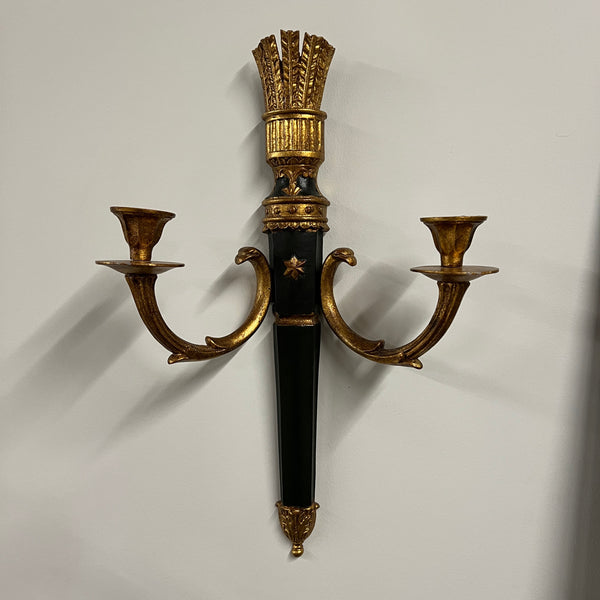 A pair of elegant wall sconces that feature an ebonized center and parcel-gilt stem supporting two gilt metal candle arms adorned with detail in the style of Louis XVI. Each center body is accented with a raised gold colored star. On the back are Palladio labels and markings.