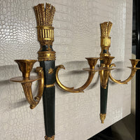 A pair of elegant wall sconces that feature an ebonized center and parcel-gilt stem supporting two gilt metal candle arms adorned with detail in the style of Louis XVI. Each center body is accented with a raised gold colored star. On the back are Palladio labels and markings.