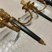 A pair of elegant wall sconces that feature an ebonized center and parcel-gilt stem supporting two gilt metal candle arms adorned with detail in the style of Louis XVI. Each center body is accented with a raised gold colored star. On the back are Palladio labels and markings.