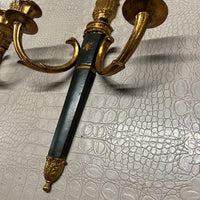A pair of elegant wall sconces that feature an ebonized center and parcel-gilt stem supporting two gilt metal candle arms adorned with detail in the style of Louis XVI. Each center body is accented with a raised gold colored star. On the back are Palladio labels and markings.