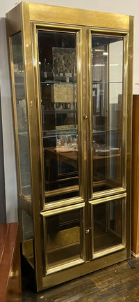 Lovely brass and glass vitrine by Mastercraft. The cabinet features 4 doors and several adjustable glass shelves. The inside of the cabinet has antique glass.
