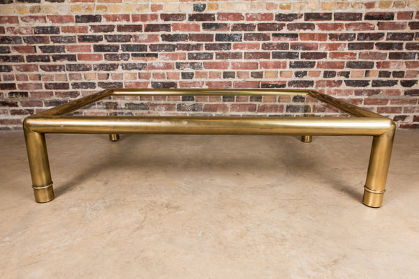 A beautiful, substantial, square brass and glass coffee table by Mastercraft. Thick tubular brass frame with subtle ring detail at the base of each leg.