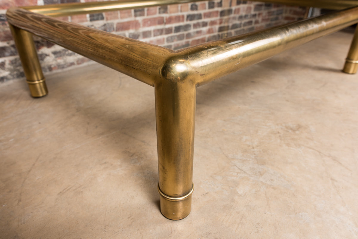 A beautiful, substantial, square brass and glass coffee table by Mastercraft. Thick tubular brass frame with subtle ring detail at the base of each leg.