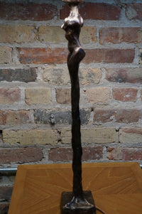 Limited Edition.  Signed and numbered bronze sculptures grace the base of this stunning table lamp that is often mistaken for a Giacometti styled female figure.   Two versions (similar yet not identical) make the perfect pair of lamps.  Rooted melds art (sculpture) and function (lamp).  Exclusive to Studio Sonja Milan.