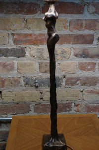 Limited Edition.  Signed and numbered bronze sculptures grace the base of this stunning table lamp that is often mistaken for a Giacometti styled female figure.   Two versions (similar yet not identical) make the perfect pair of lamps.  Rooted melds art (sculpture) and function (lamp).  Exclusive to Studio Sonja Milan.